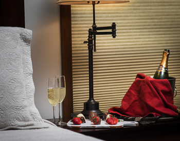 Picture of nightstand with two glasses of champagne and chocolate covered strawberries.